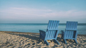 Two empty deckchairs on the sand facing the sea