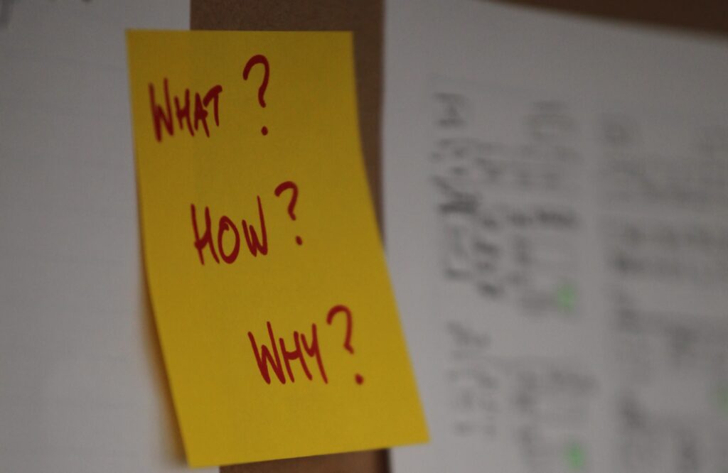 Post-it note on wall with 'What?', 'How?' and 'Why' written on it