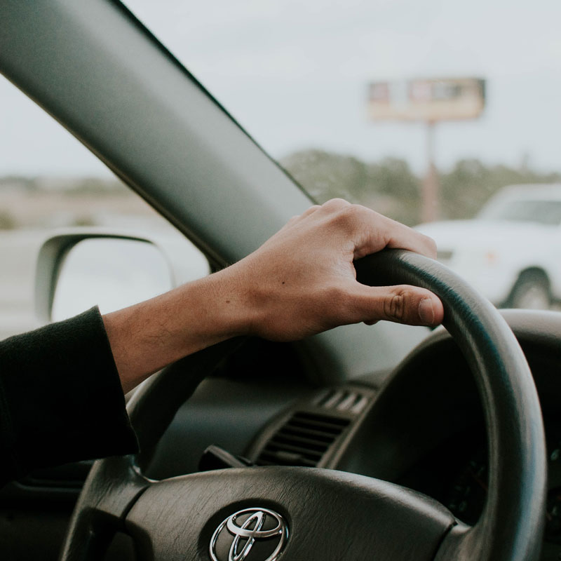 Hand on steering wheel of car