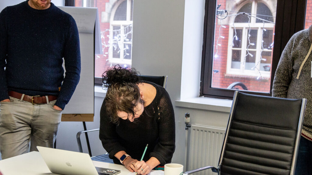 Person writing with a laptop on the table