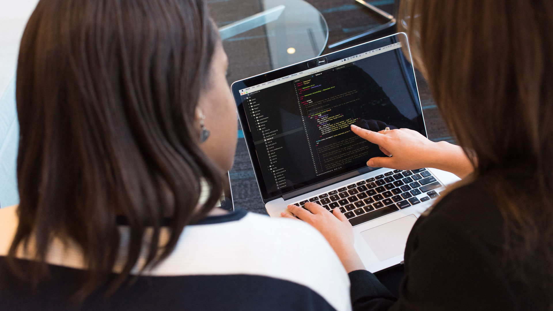 Two people looking at a screen with code on it