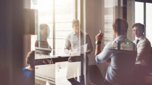 Group of people in a room with glass walls, having a discussion