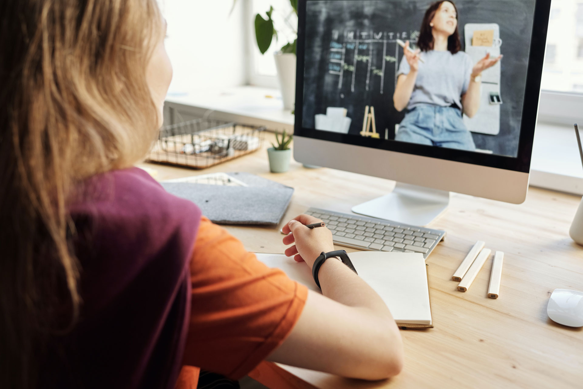 Student looking at screen with teacher and blackboard on it